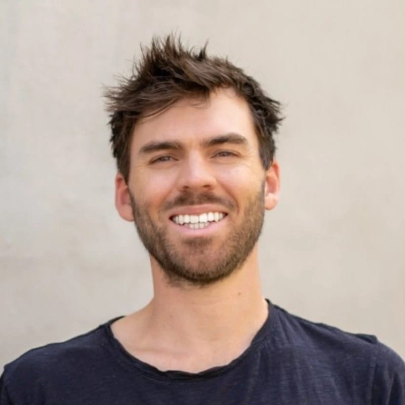 Smiling person with tousled hair against a neutral background.