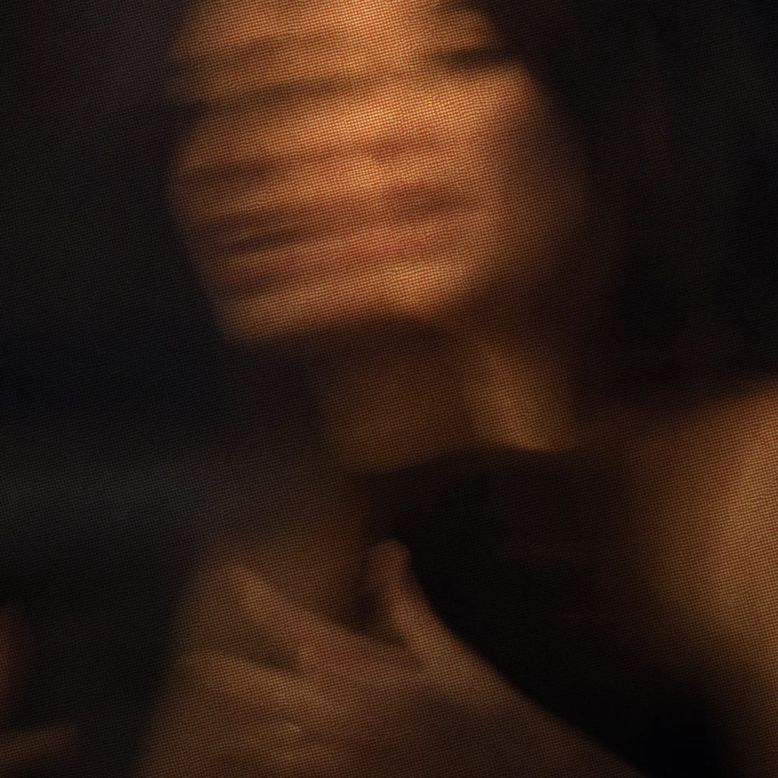 Blurred image of a person with hand near their face, creating a sense of motion and ambiguity.