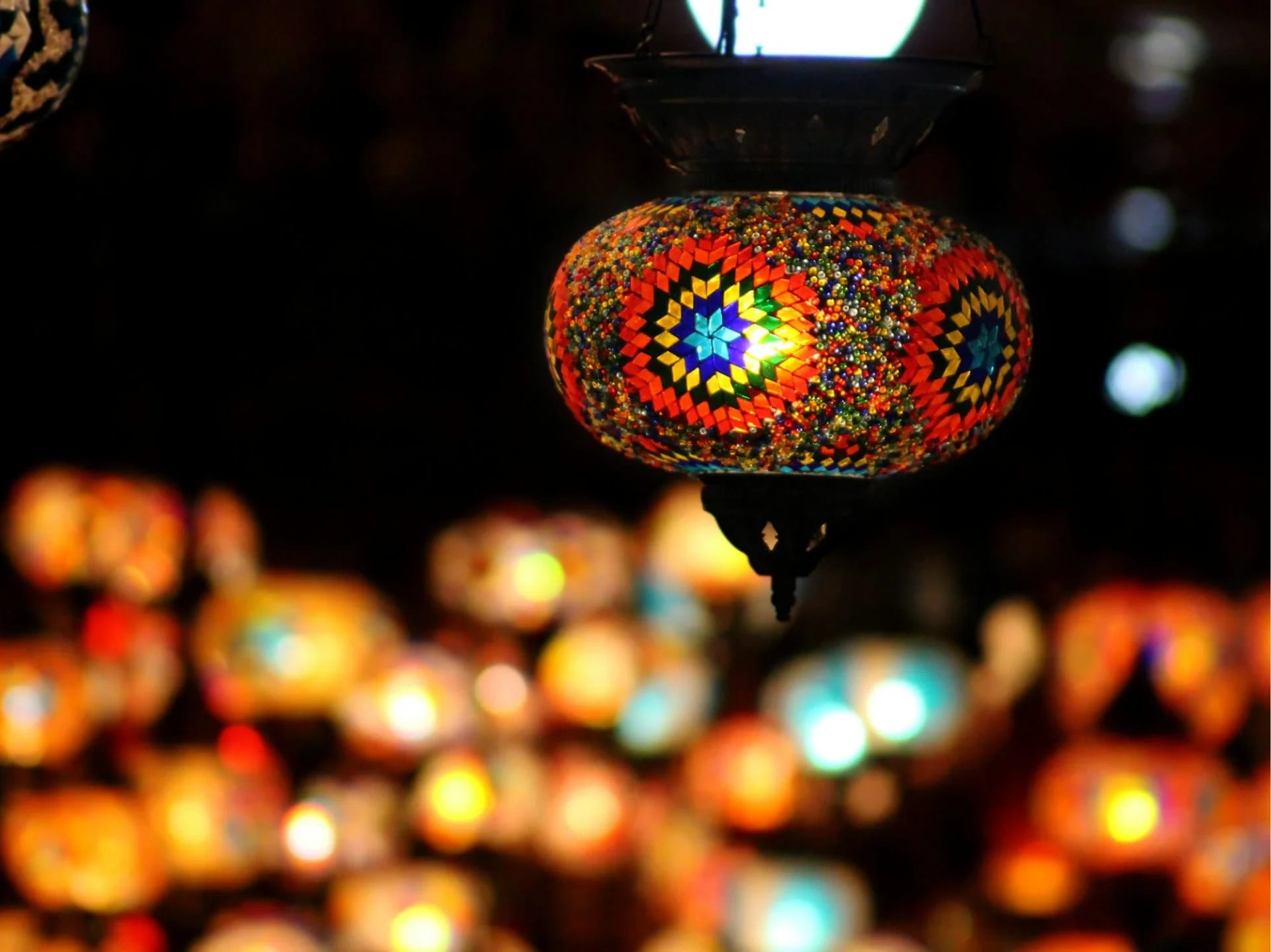Colorful mosaic lantern hanging in a dark space.
