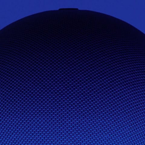 Close-up of a textured blue speaker cover against a dark blue background.