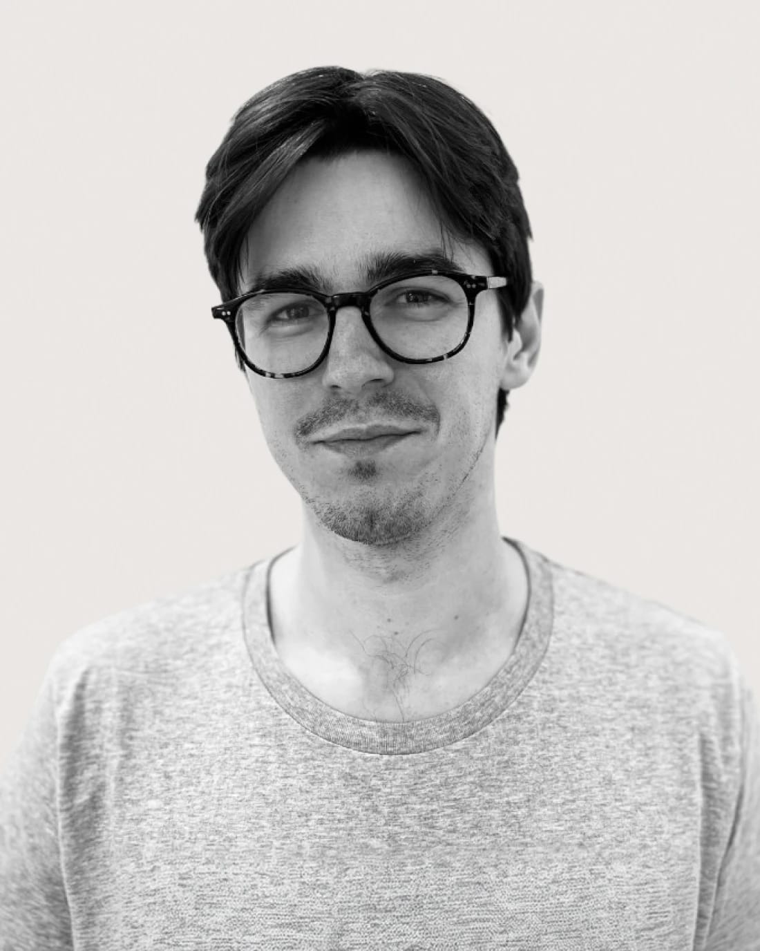 Portrait of a bespectacled man with dark hair wearing a gray T-shirt.