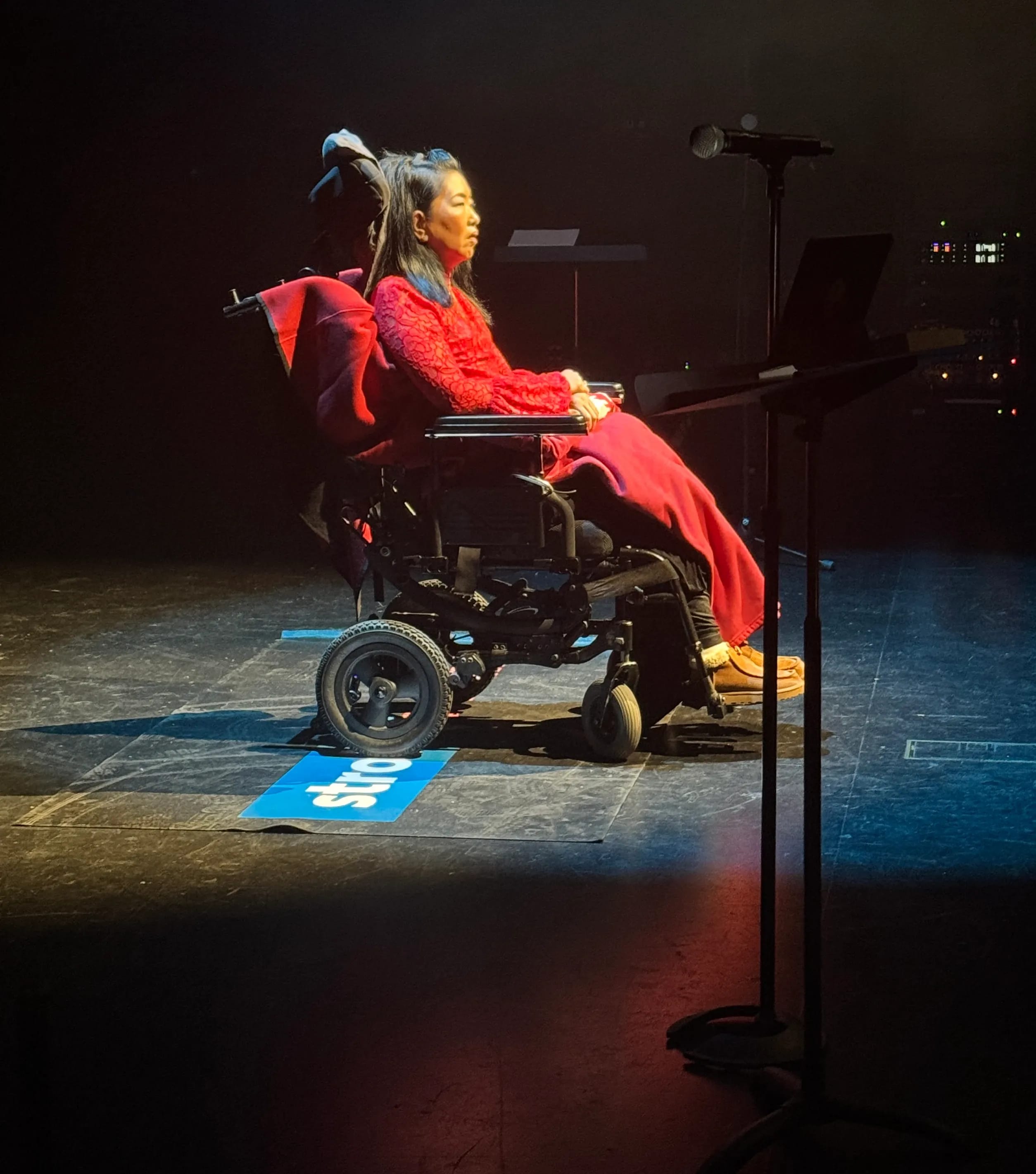 Woman in a red dress sitting on stage in a wheelchair