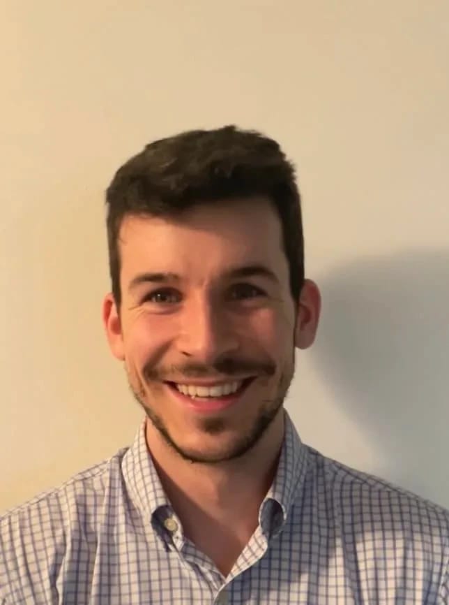 Man smiling, wearing a checkered shirt against a plain background.