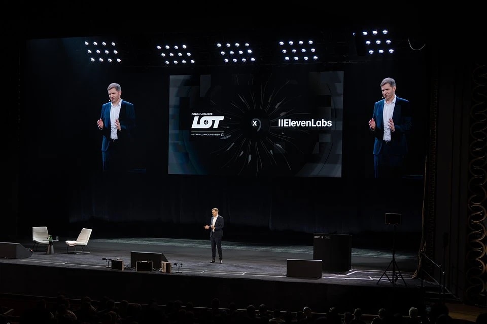 Michał Fijoł, CEO at LOT Polish Airlines on stage with LOT and ElevenLabs logos displayed on a large screen.